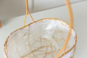 Close-up of golden iron flower basket with delicate white lace trim and inner lining