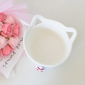Close-up of woven cotton rope storage basket with cute cat ear handles and cat ornament