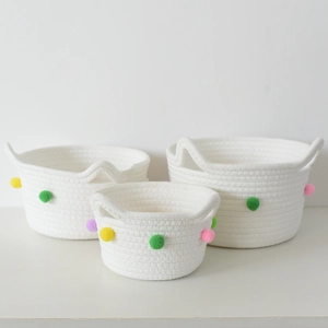 Detailed macro view of white woven cotton rope storage baskets with colorful pom-pom decor