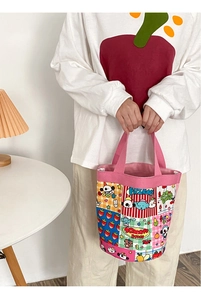 Close-up of cute cartoon patchwork canvas bucket bag held by hand in home setting