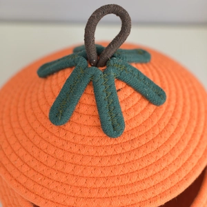 Close-up of a pumpkin-shaped cotton woven basket lid with green leaf detail