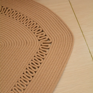 Close-up detail of wave-pattern cotton rope weaving on a handmade brown earthy rug