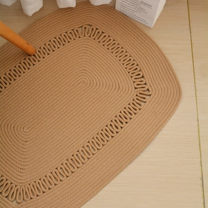 Macro detail of oval hand-woven jute rug featuring decorative wavy braided edges