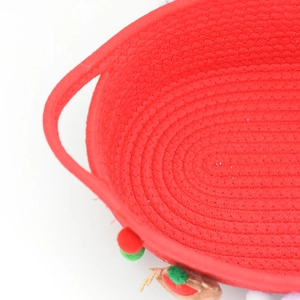 Close-up of red woven Christmas basket with spiral texture and festive pom-pom trim