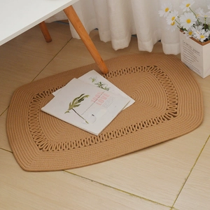 Detail of khaki oval cotton rope woven rug with decorative openwork pattern in cozy room