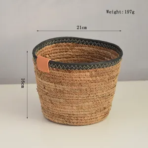 Detail of handwoven seagrass storage basket with black trim and brown leather handle