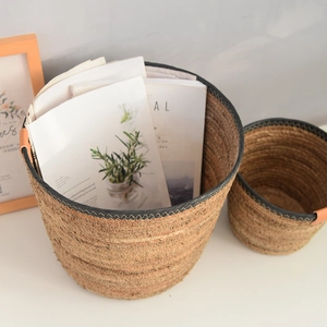 Handwoven straw baskets with leather handles and black trim details for home storage