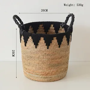 Detail of hand-woven straw basket with black tassels and dual handles, 26x25cm