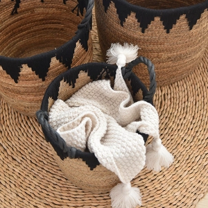 Detailed macro view of three handwoven seagrass storage baskets with black tassel patterns