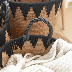 Detail of hand-woven straw basket featuring black fringe and sturdy rope handles