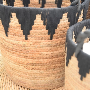 Close-up of woven seagrass basket texture with black cotton fringe and tassel details