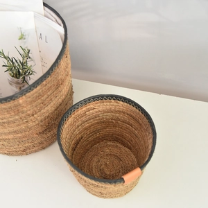 Detail of handcrafted seagrass storage baskets with black trim and leather accents