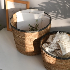 Close-up of woven storage baskets with black leather trim and soft white knit blanket