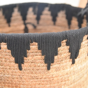 Detail of handwoven seagrass storage basket featuring ethnic black geometric edge patterns