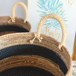 Close-up of handwoven seagrass storage basket with black stripes and rope handle detail