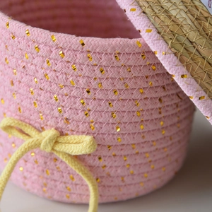 Dettaglio di cesto in cotone intrecciato rosa con paillettes dorate e fiocco giallo