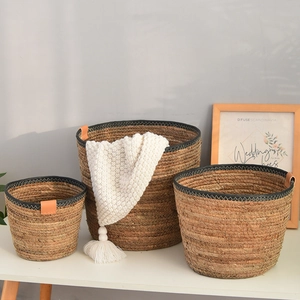 Three-piece set of woven seagrass storage baskets with black trim and leather details