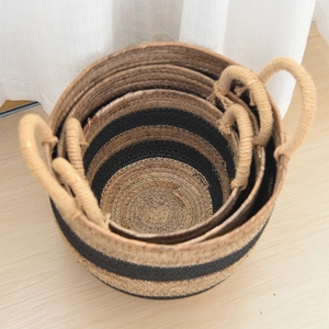Detail of natural seagrass storage baskets with black stripes and rope handles