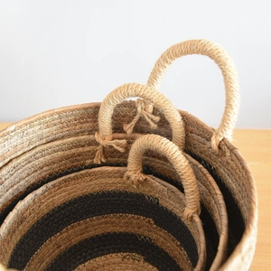 Detail of woven seagrass storage baskets with brown stripes and sturdy rope handles