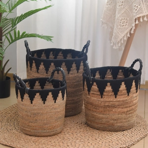 Macro detail of three handmade straw storage baskets with black zigzag patterns and handles