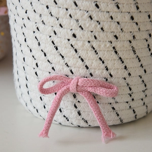 Dettaglio del cestino in corda di cotone intrecciata a mano con un fiocco rosa decorativo