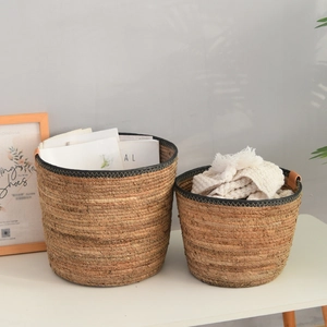 Detail of woven straw storage baskets with brown leather handles and black stitching