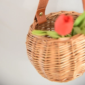 Close-up of woven willow storage basket with brown leather handle and metal rivets