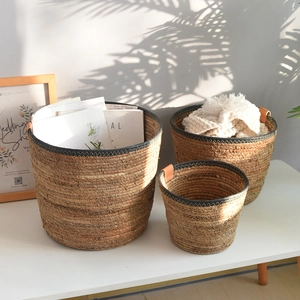 Detailed close-up of natural seagrass storage baskets with leather handles and black trim