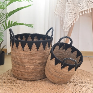 Detail of handmade straw storage baskets with black wave fringe and carrying handles