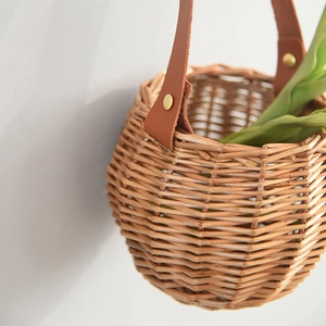 Handwoven willow wall hanging basket with brown leather handle and gold rivet details