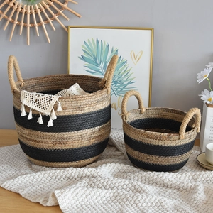 Detail of woven rattan storage baskets with black stripes and decorative white tassels