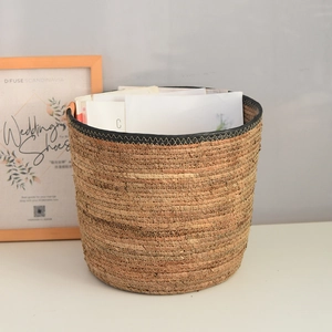 Detail of handwoven cylindrical grass storage basket with durable black reinforced rim