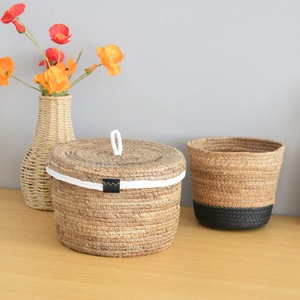 Detailed close-up of natural woven grass storage basket with lid and leather buckle