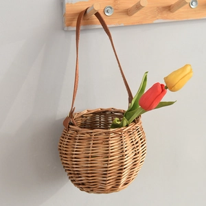 Close-up of woven willow basket with leather handle hanging on wall with tulips