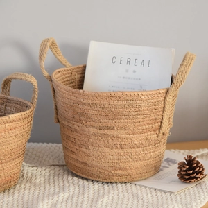 Detail view of a Nordic woven storage basket with dual handles on a soft white knit blanket