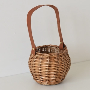 Close-up of natural willow basket weave pattern with brown leather handle and gold rivet detail