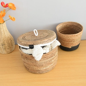Detail of woven storage baskets with lids and black stitching on natural straw texture