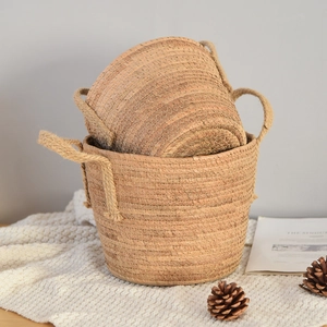 Close-up of woven straw plant baskets with rustic hemp rope handles on a cozy white rug