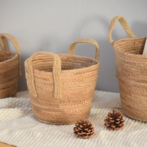 Three sizes of Nordic woven straw storage baskets with thick rope handles on white blanket