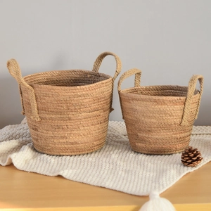 Detailed view of two natural seagrass woven baskets with handles on a cozy fabric
