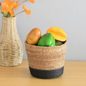 Detail of hand-woven round storage basket featuring a unique two-tone black and beige design