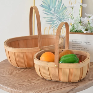 Detail of two handmade woven storage baskets with wooden handles on a rustic table