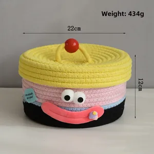 Detail view of woven storage basket with cartoon face and red bead handle on the lid