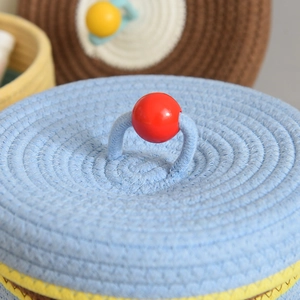 Detailed macro view of light blue woven cotton storage basket with red bead on the lid