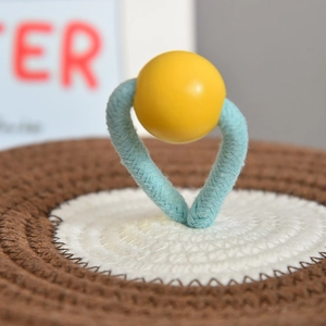 Detail of hand-woven storage basket lid with light blue handle and yellow bead