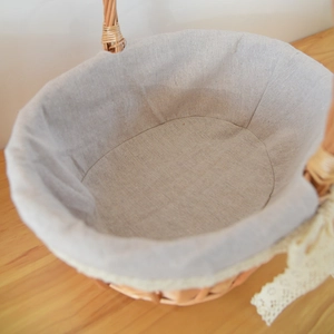 Close-up of handwoven wicker basket with grey linen liner and delicate white lace trim