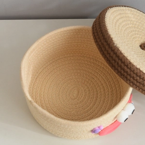 Close-up of handwoven round storage basket with lid featuring a cute cartoon face design