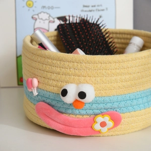 Detailed view of woven cotton rope storage basket with cute cartoon face and soft texture