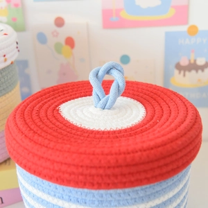 Close-up of woven storage basket with blue stripes and a red-white circular patterned lid