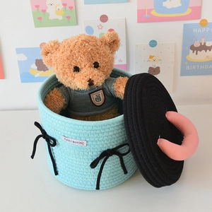 Close-up of light blue woven cotton storage basket with black bow and cute teddy bear
